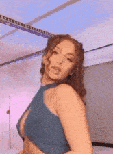 a woman with curly hair is dancing in a blue top .