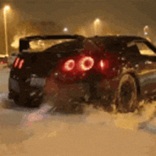 a car is driving through the snow at night with its lights on