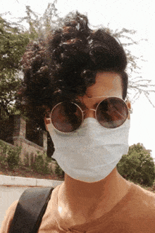 a man wearing a mask and sunglasses looks at the camera