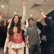 a group of people are dancing together in a room with their arms in the air .