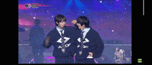 two men are standing next to each other on a stage in front of a sign that says mix festa .