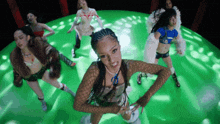 a group of women are dancing in a circle on a green stage