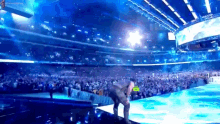 a man is kneeling on a stage in front of a crowd .