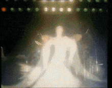 a woman in a white dress stands on a stage