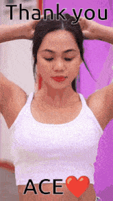 a woman in a white tank top is holding her hair with her hands .