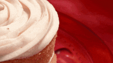 a close up of a cupcake with pink frosting on a red plate