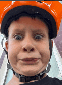 a child wearing an orange helmet making a funny face
