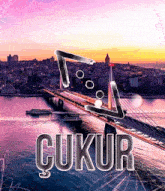 a bridge over a body of water with a city in the background and the word ' ukur ' in the foreground