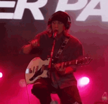 a man is singing into a microphone while playing a guitar on stage