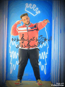 a man in a red jacket stands in front of a blue wall