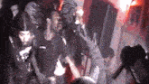 a group of people are dancing in a dark room while a man is singing into a microphone .