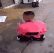 a person in a pink shirt is riding a go kart on the sidewalk .