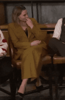 a woman in a suit sits in a chair laughing