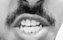 a black and white photo of a man 's mouth with a beard and teeth .