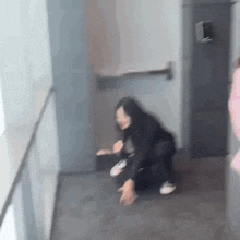 a blurry picture of a woman kneeling on the floor in a hallway .