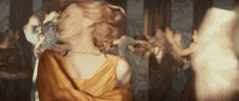 a woman in a yellow dress is dancing in front of a crowd of people