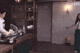 a woman is dancing in a kitchen while another woman does dishes .