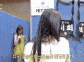 a woman stands in front of a sign that says ' hits ' on it