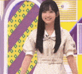 a young woman in a white dress is smiling in front of a yellow and purple background .