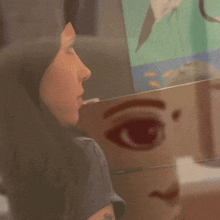 a painting of a woman 's face is reflected in a wall
