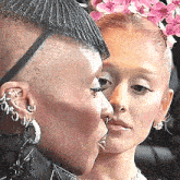 a man and a woman are kissing in front of a mirror . the woman is wearing a flower crown .