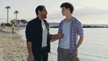 a man in a purple shirt is standing next to another man on a beach