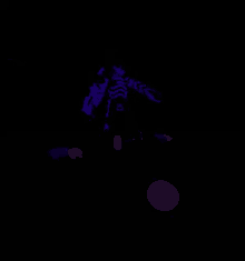 a person is laying on the ground in the dark with a purple light behind them .
