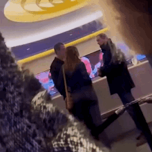 a man and a woman are standing next to each other in a room talking to each other .