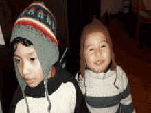 a boy and a girl wearing knitted hats are standing next to each other