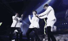 a group of men are standing on a stage holding microphones and dancing .