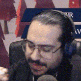 a man wearing glasses and headphones is sitting in front of a microphone