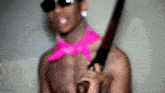 a shirtless man wearing a pink bandana and sunglasses is holding a large knife .