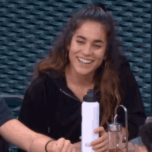 a woman is smiling while holding a white water bottle that says ' altitude ' on it