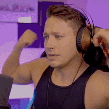 a man wearing headphones is flexing his muscles in front of a laptop