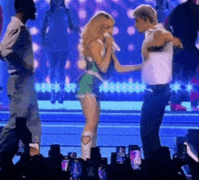 a woman singing into a microphone while standing next to a man