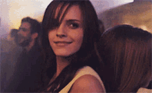 a woman with long brown hair is smiling in a crowd of people
