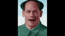 a close up of a man wearing a green suit and a hat .