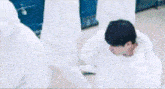 a man in a white hoodie is standing in front of a row of white walls .