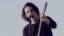 a man is singing into a microphone while playing an electric guitar .