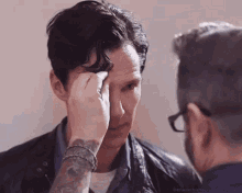 a man with a tattoo on his arm is getting his hair done