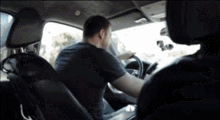 a man in a black shirt is sitting in a car