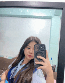 a girl taking a picture of herself in a mirror with a lanyard around her neck that says ' benito ' on it