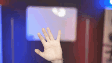 a person 's hand is reaching up in front of a screen
