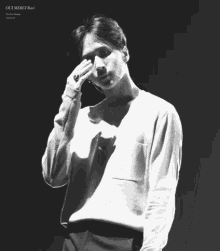 a black and white photo of a man holding his head .