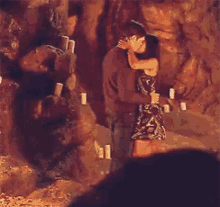 a man and a woman are kissing in front of a waterfall