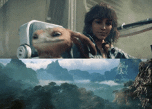 a woman holding a small animal next to a landscape with mountains