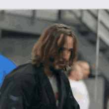 a man with long hair and a beard is standing in front of a mirror