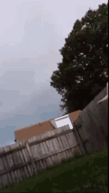 a person is jumping over a wooden fence with a house in the background