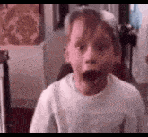a young boy is making a surprised face with his mouth open in a room .
