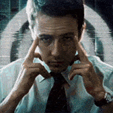 a man with his hands on his forehead looks at the camera